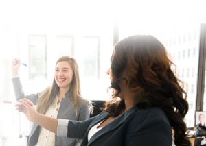 Two ladies working on a white board